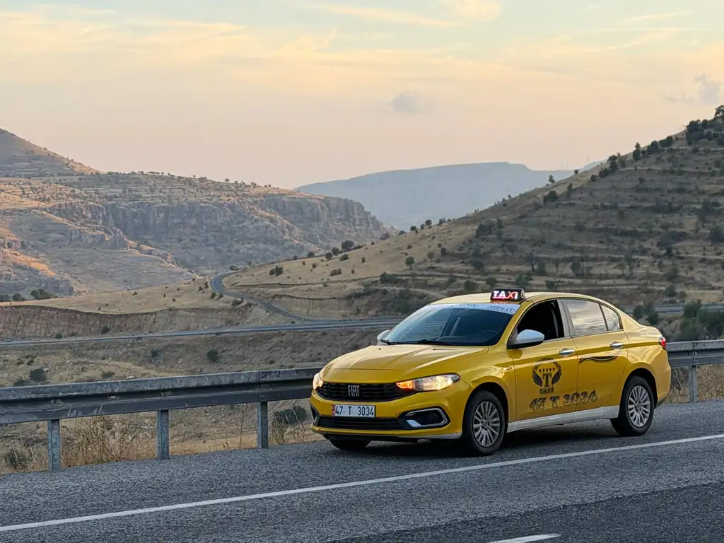 Midyat çevresinde dağ yolunda sarı Midyat Taksi 7/24 aracı