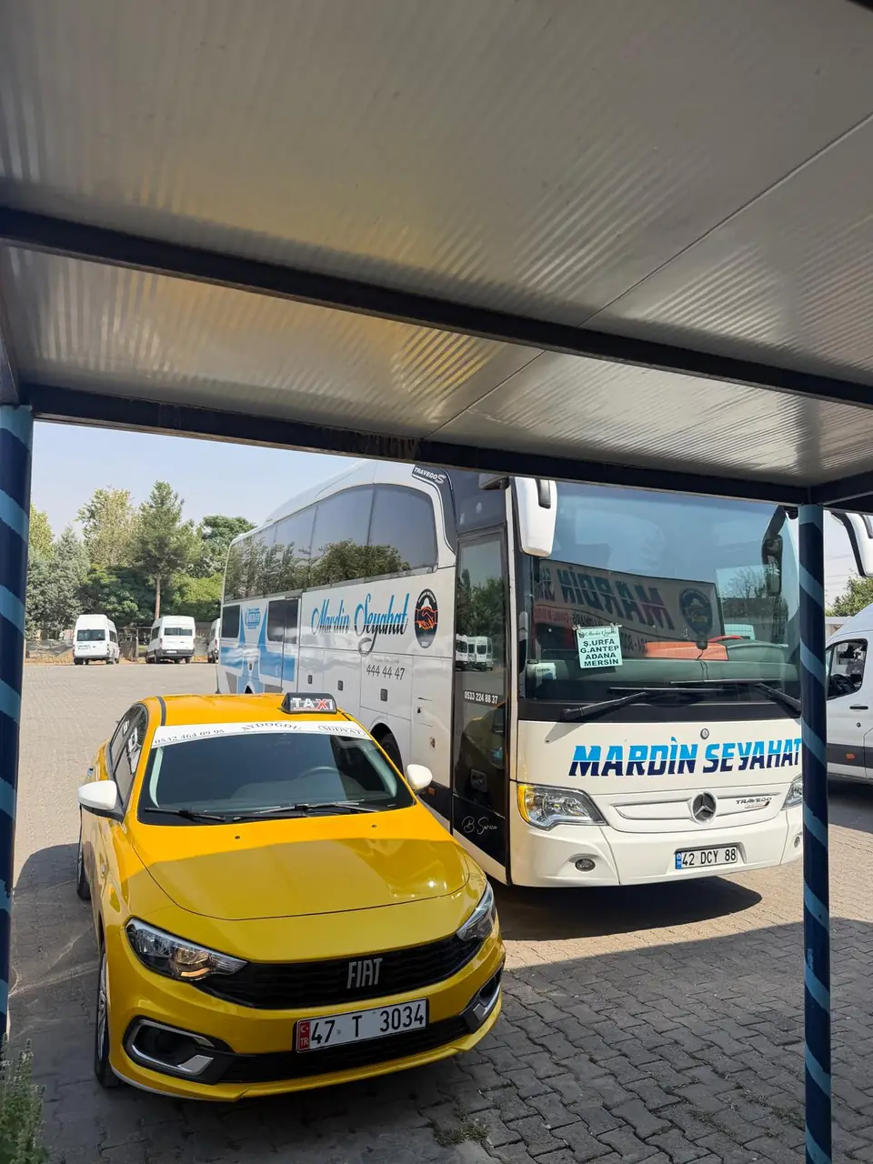 Midyat otogarında otobüs yanında bekleyen sarı taksi